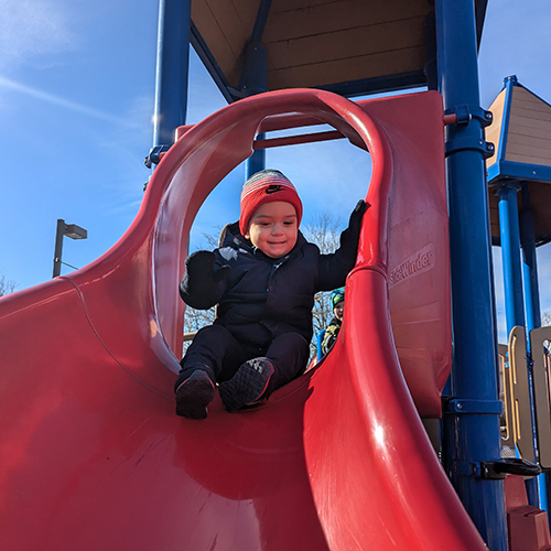 Preschool photo of smiling boy on slide